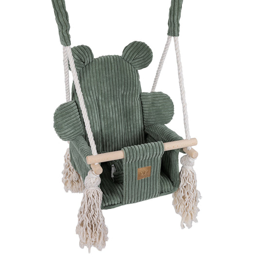 Olive green baby swing hanging from rope with fringe detail and wooden bar, angled view