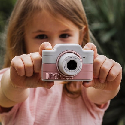 Fetiță care ține aparatul foto roz Hoppstar Expert Blush spre privitor