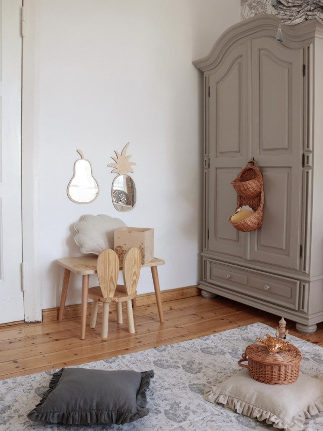 Two wooden mirrors including pineapple design displayed in minimalist playroom setting