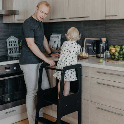 Black Montessori kitchen tower with child drawing at counter in modern kitchen