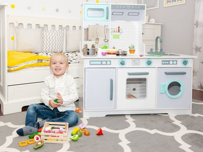Toddler playing with wooden kitchen set in bedroom with accessories and toy food scattered around
