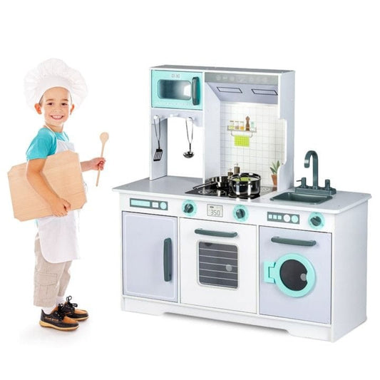 Child wearing chef hat holding wooden play kitchen with microwave, oven, washing machine and sink