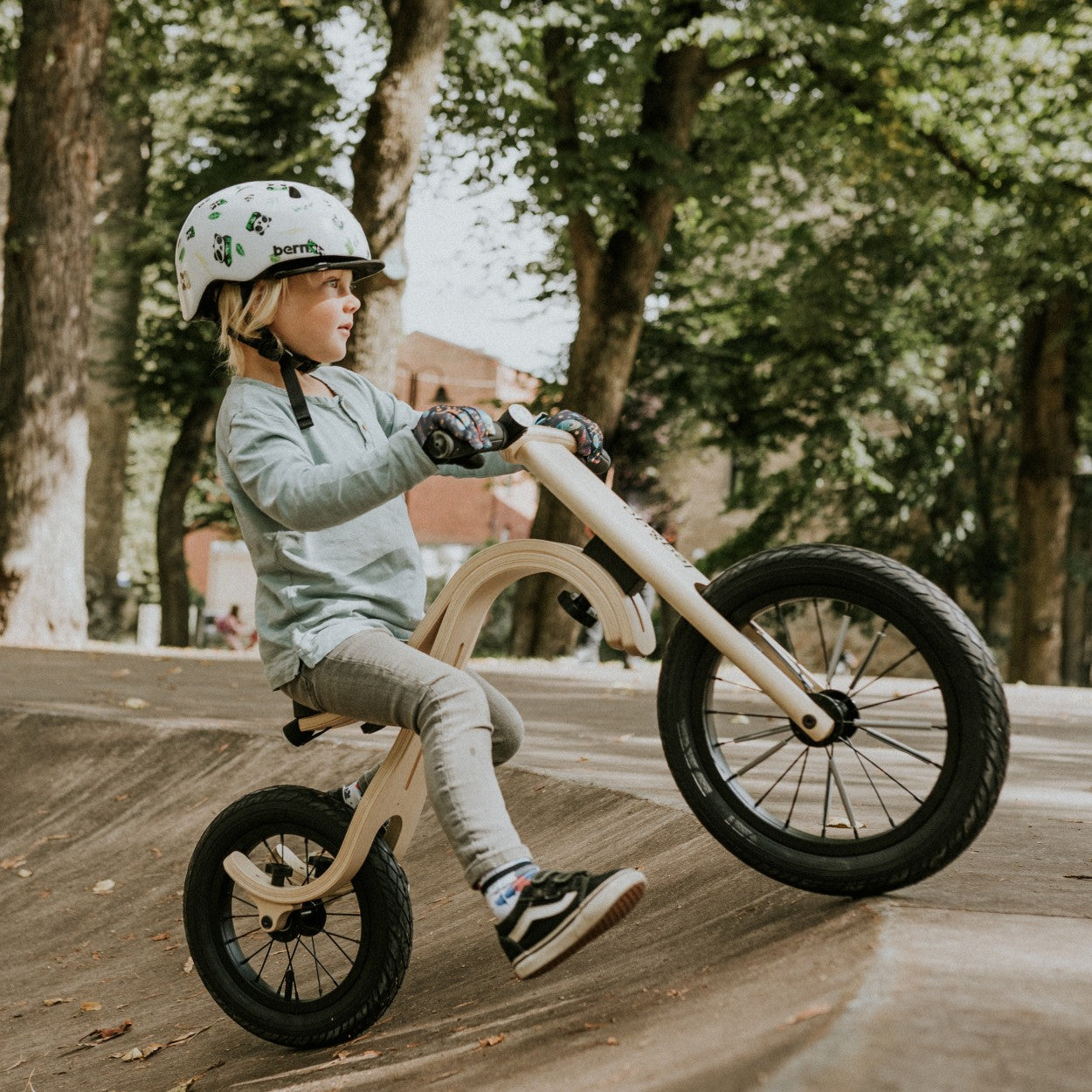 Child in helmet riding leg&go wooden balance bike 3in1 outdoors – active toddler bike lifestyle
