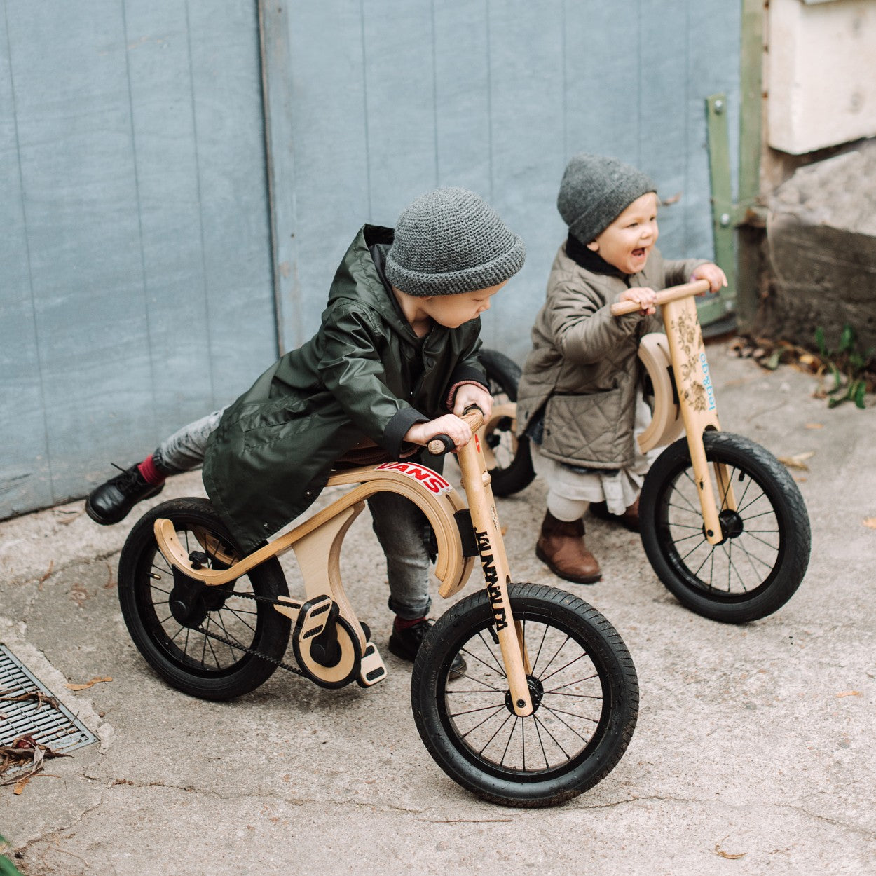 Two children riding leg&go balance bikes with pedals on urban street