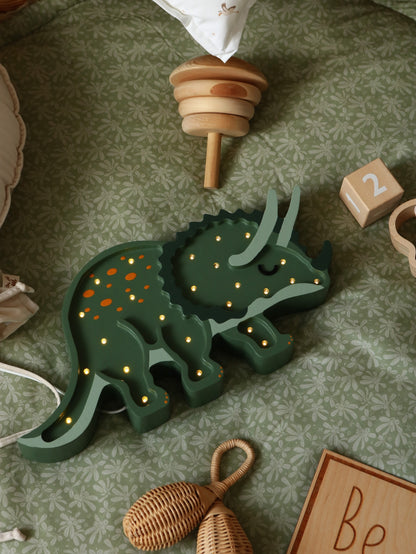 Green triceratops dinosaur lamp with warm white LED lights on a bedroom floor