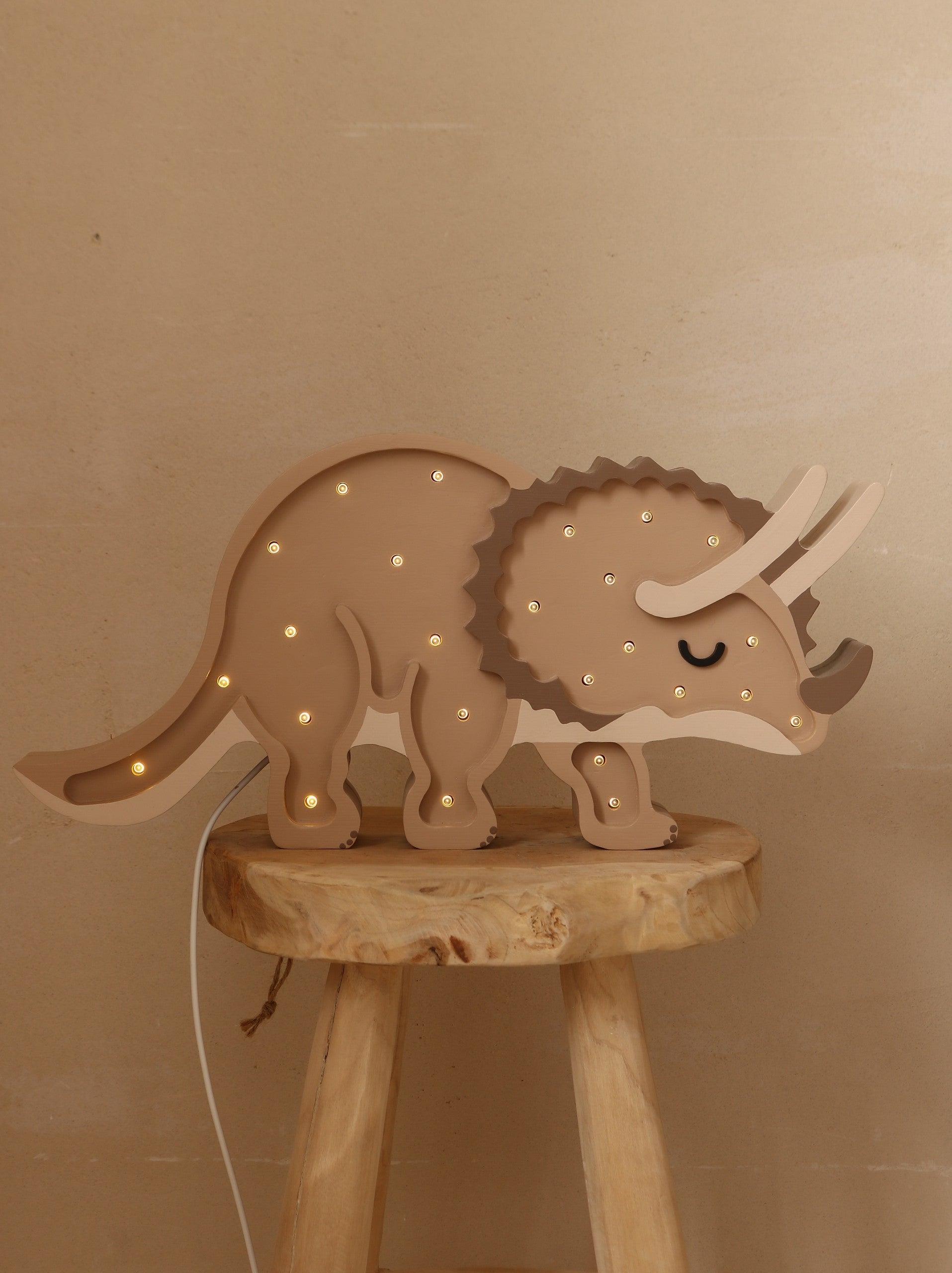 Natural wood triceratops lamp with glowing LED lights displayed on a wooden stool