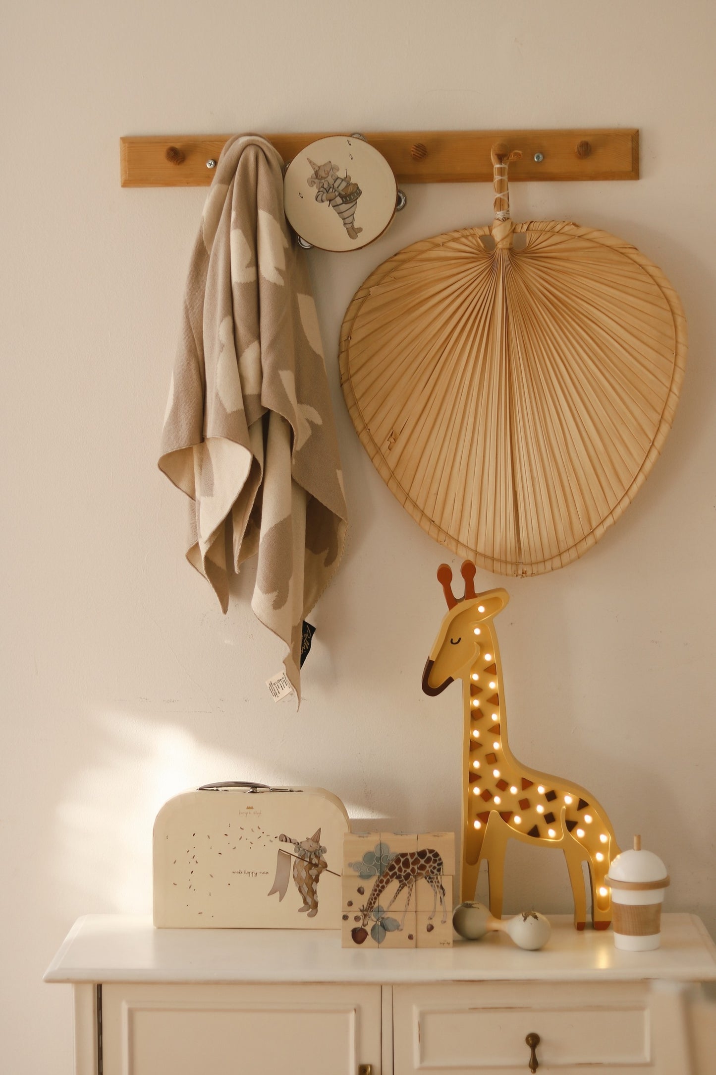 Giraffe lamp glowing on white dresser with woven heart decal and decorative accessories