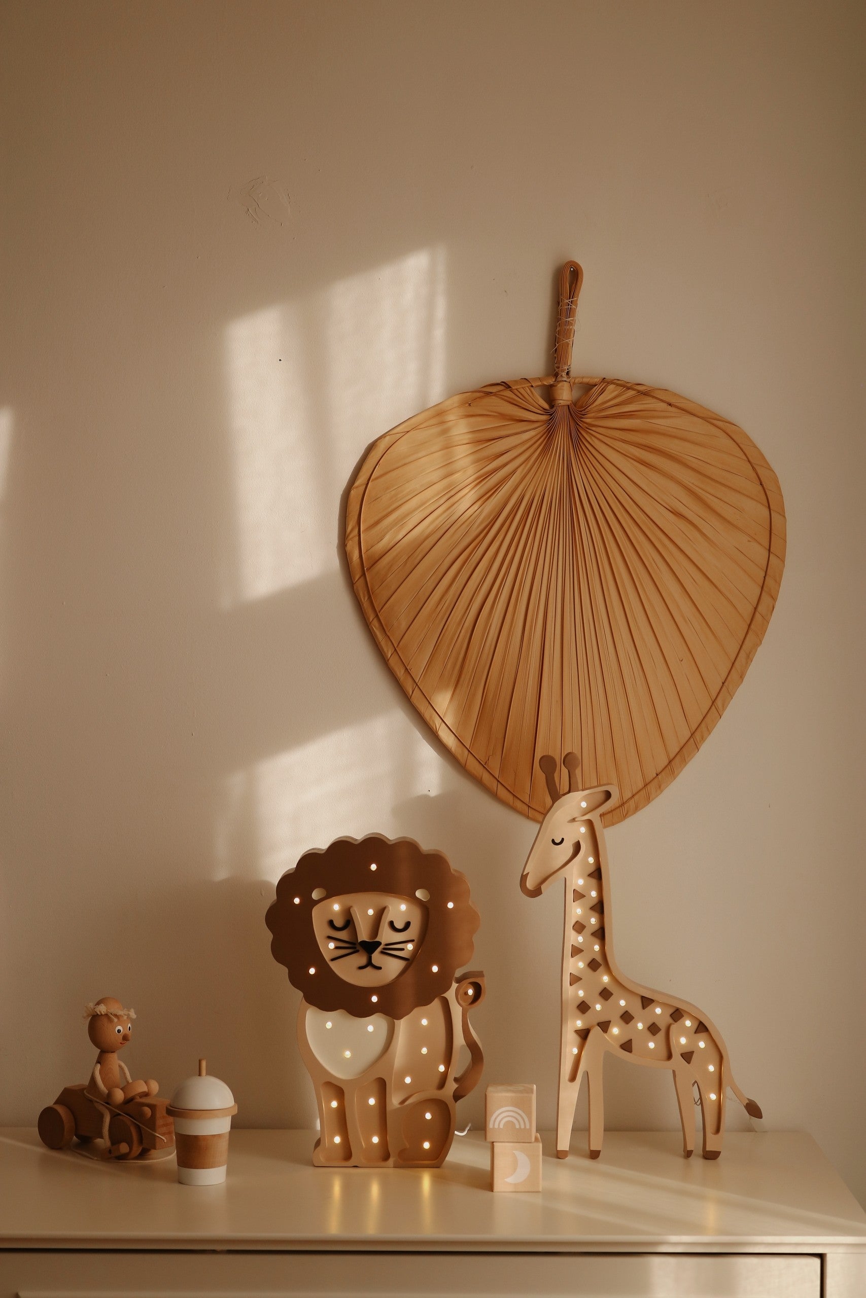 Warm white giraffe lamp illuminated next to lion lamp and woven heart wall decal