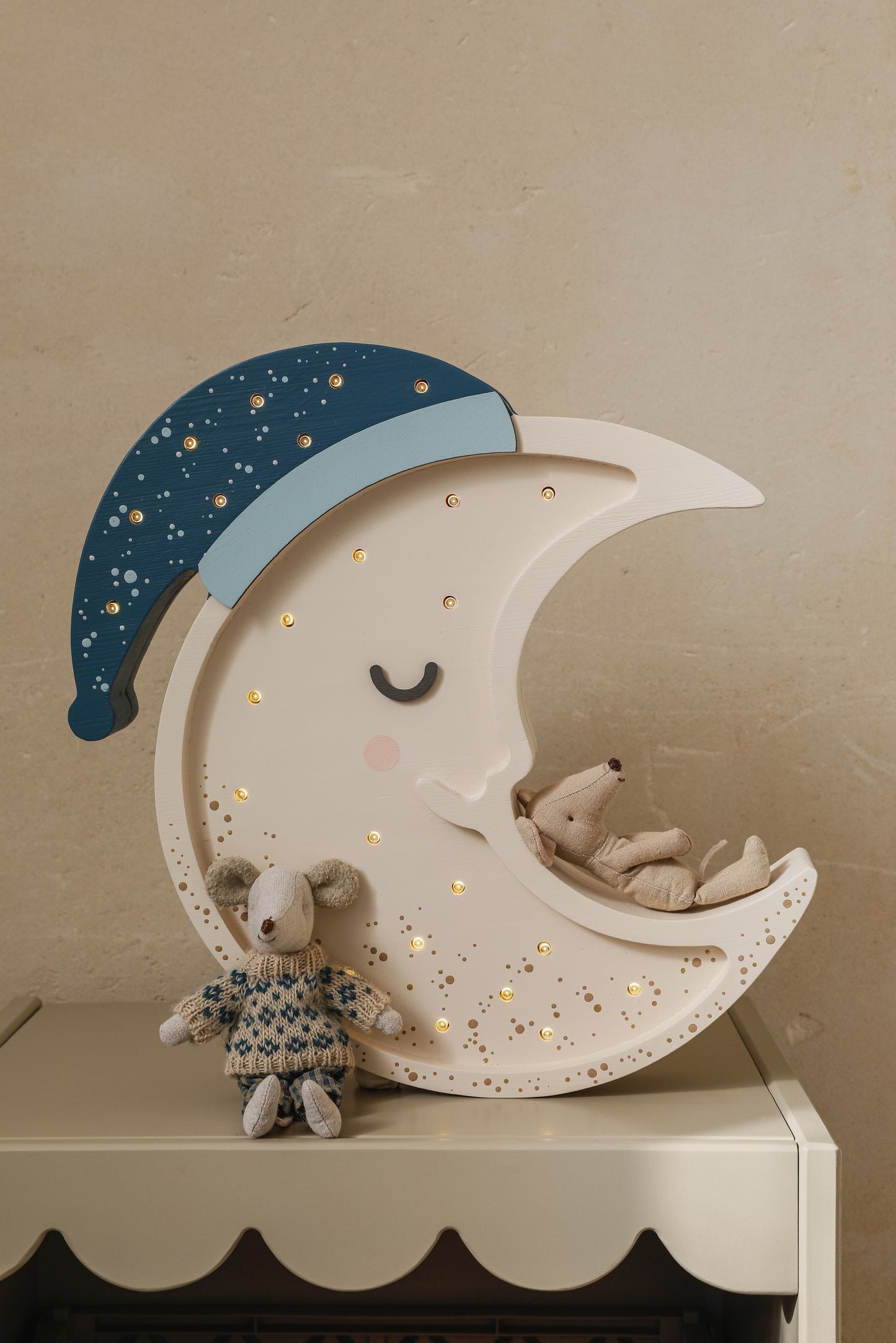 Moon lamp showing LED lights inside with blue nightcap and storage pocket, displayed on dresser