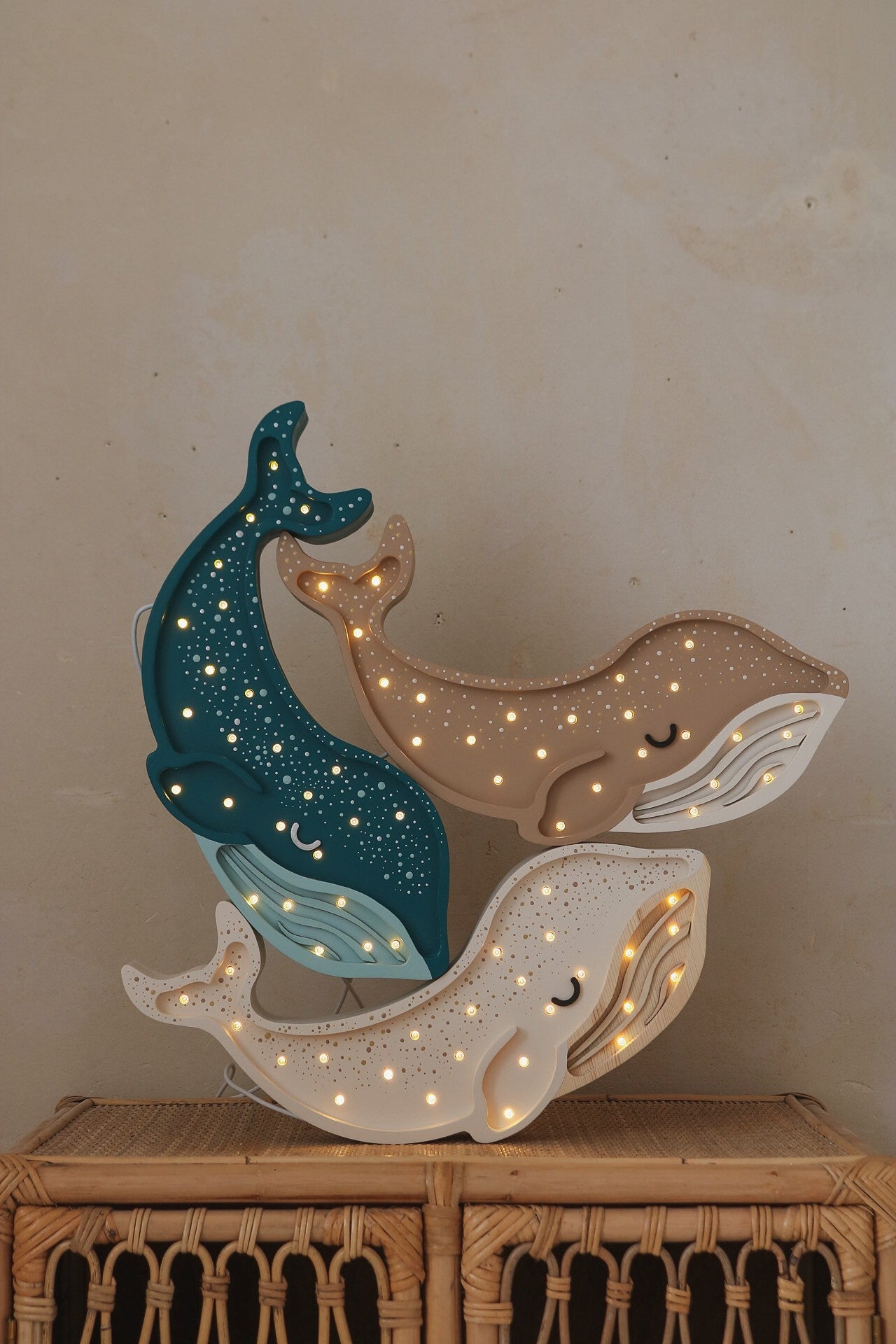 Little Lights whale lamp stacked display with dark teal, tan and cream wooden whale shapes lit with warm white LED lights