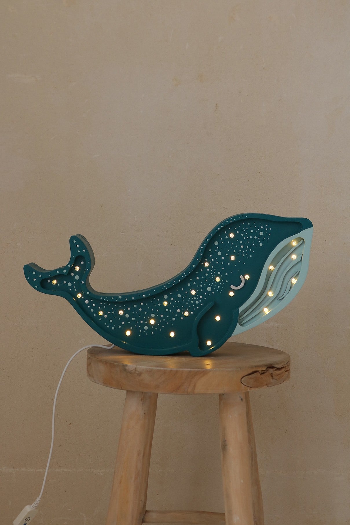 Dark teal whale lamp with LED constellation lights on natural wood pedestal table