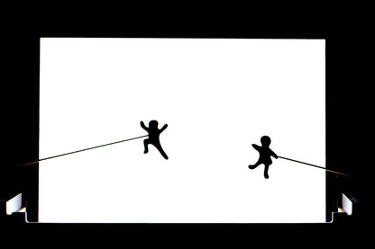 Two stick figures playing on a bright white light board panel