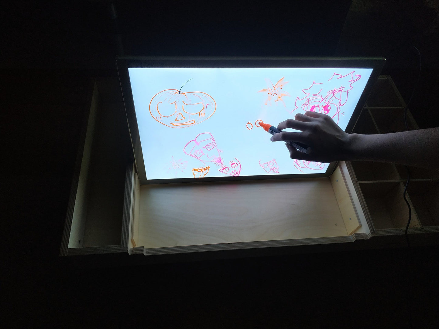 Child drawing colorful designs on illuminated LUULA light board