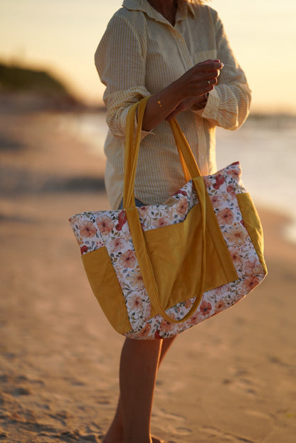 Woman carrying floral weekender bag on beach at sunset, side view