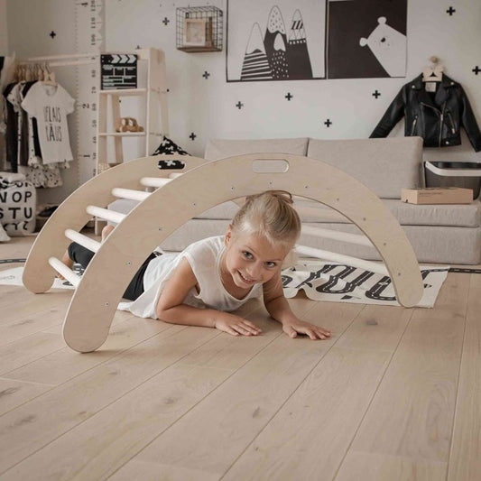 Young child crawling through birch wood climbing arch in modern bedroom