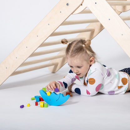 Toddler playing under wooden climbing triangle with toy basket