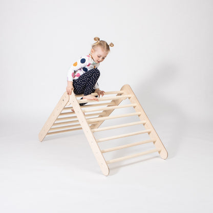 Young child climbing wooden climbing triangle showing climbing rings and slope