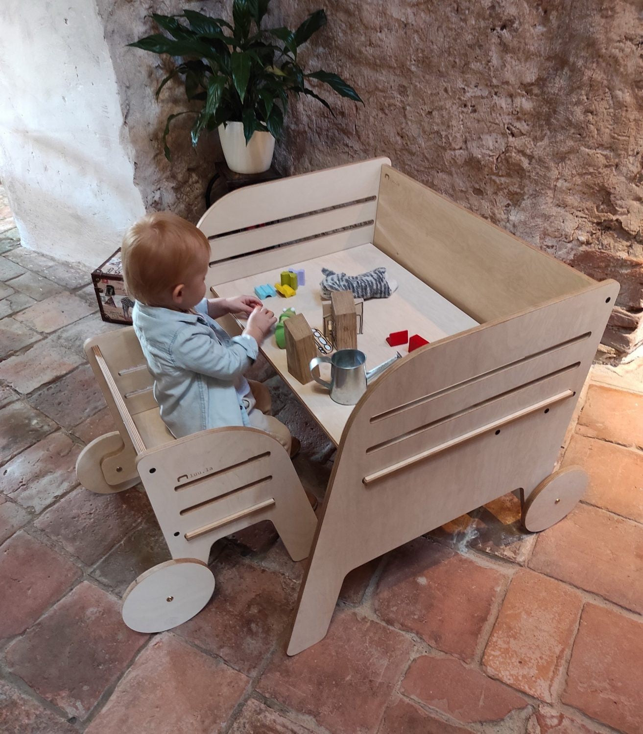 Child engaged in creative play at Luula Julle Montessori table with birch-plywood construction