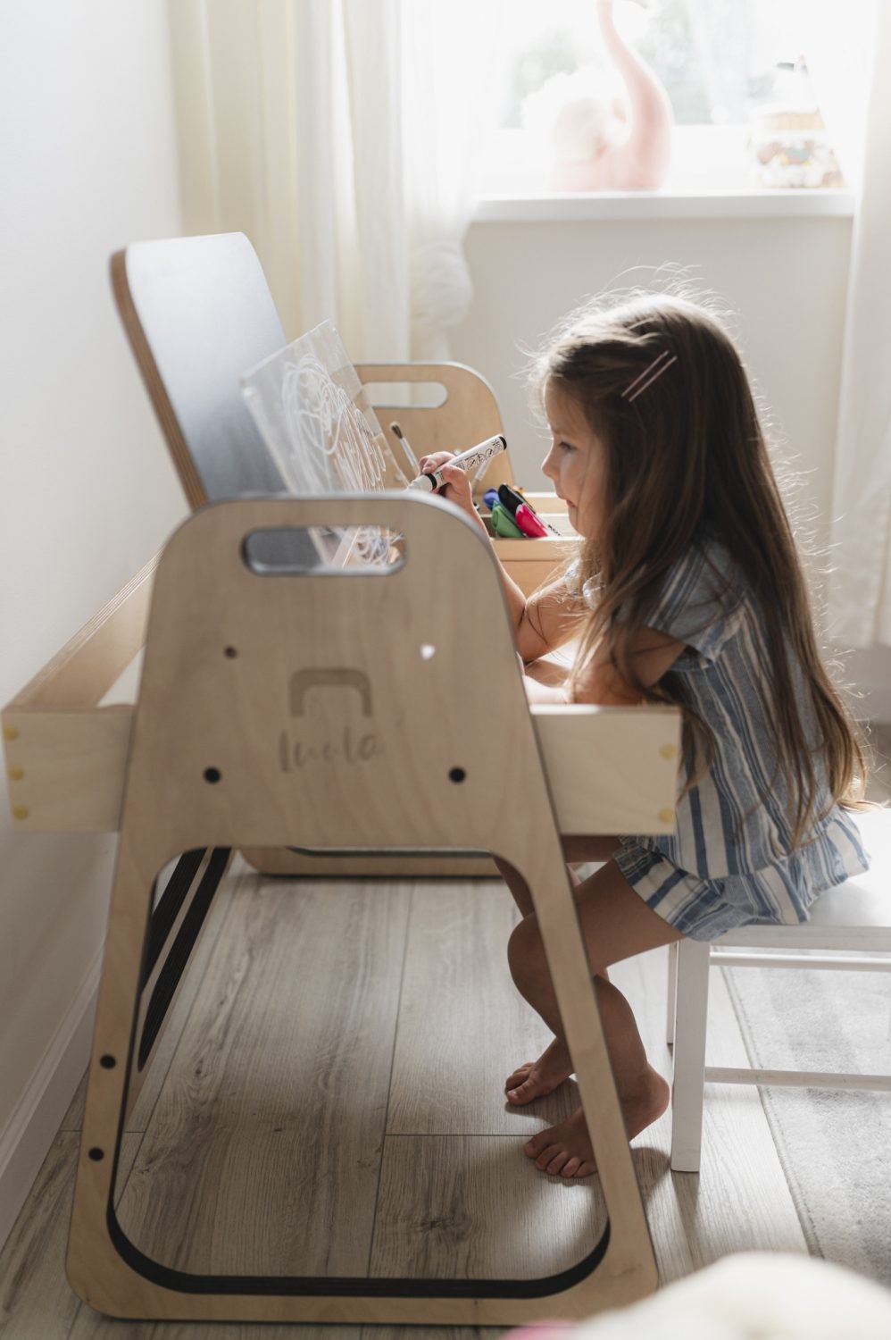 Girl seated at Luula Julle desk using whiteboard and accessing side storage
