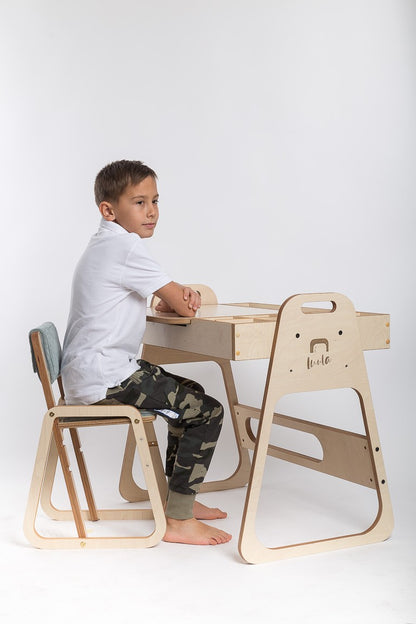Boy using Julle art and activity table with organized supplies and workspace