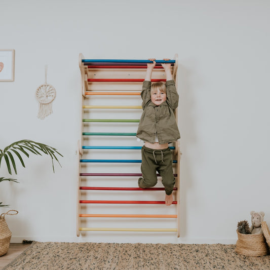 Young child climbing rainbow Swedish wall with colorful bars in modern home setting