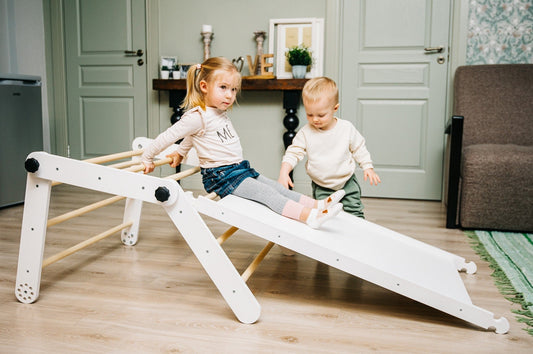 Two toddlers playing on white Pikler triangle in flat position as climbing ramp in living room