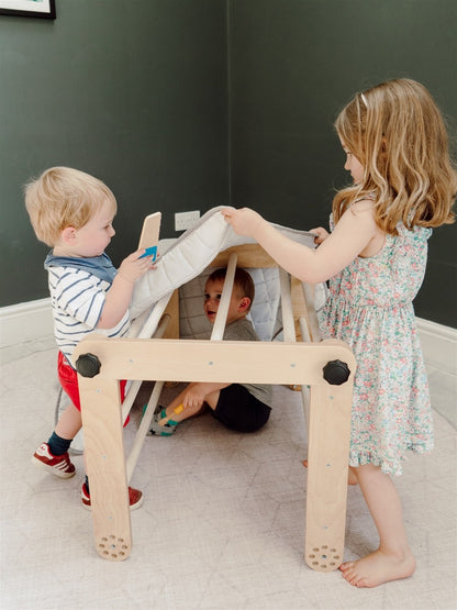 Three children playing together on natural wood Pikler triangle in multiple configurations