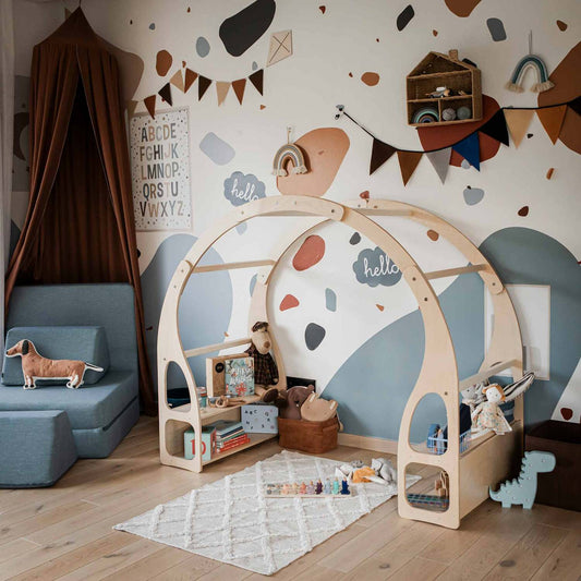 Wooden Montessori house bed play stand in styled nursery with decorative wall elements and toys