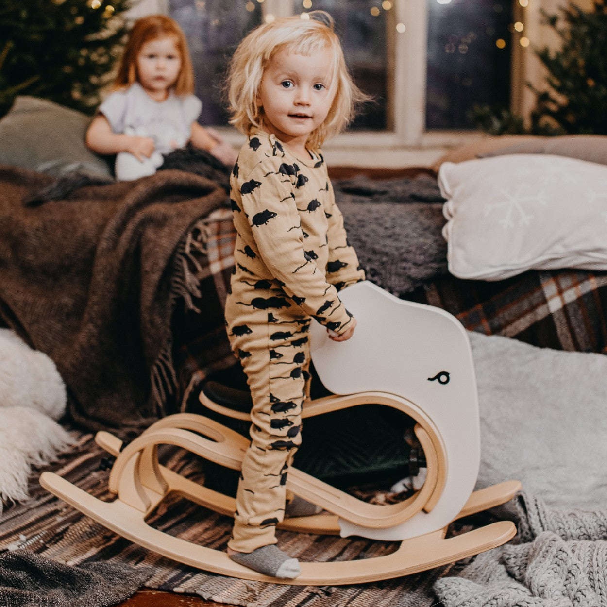 Toddler playing on white and wood rocking elephant in cozy home nursery setting