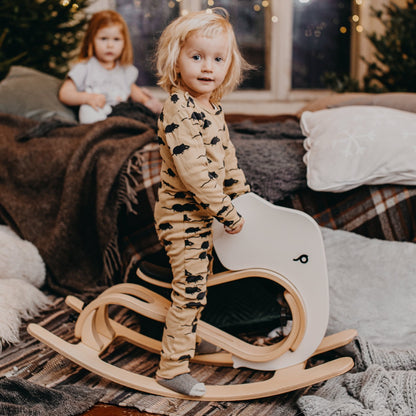 Toddler playing on white and wood rocking elephant in cozy home nursery setting