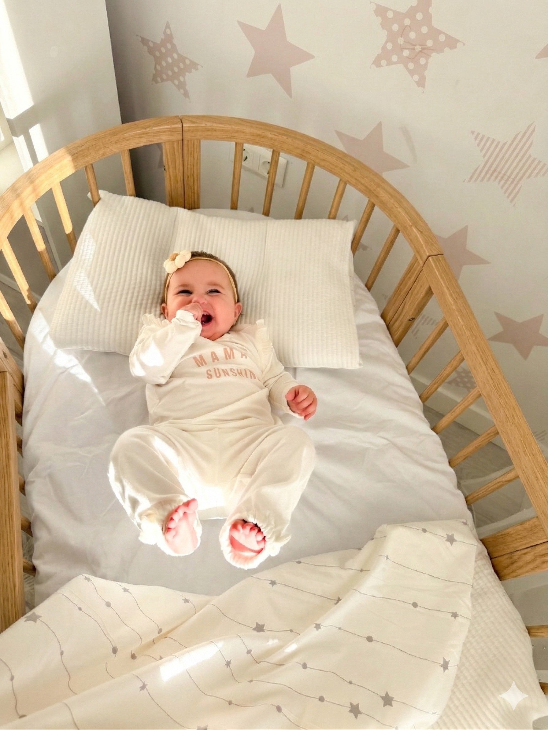 Overhead view of sleeping newborn in round crib with star pattern bedding