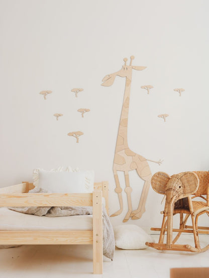 Tall wooden giraffe wall decal above wooden bed with coordinating acacia tree wall stickers in child's bedroom