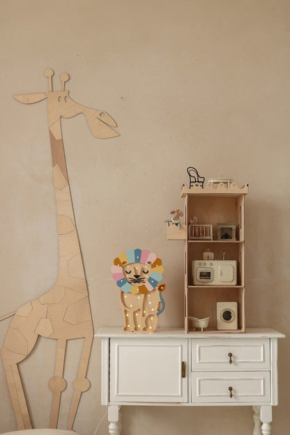 Wooden giraffe wall decor next to wooden shelving unit with toy kitchen setup and decorative items