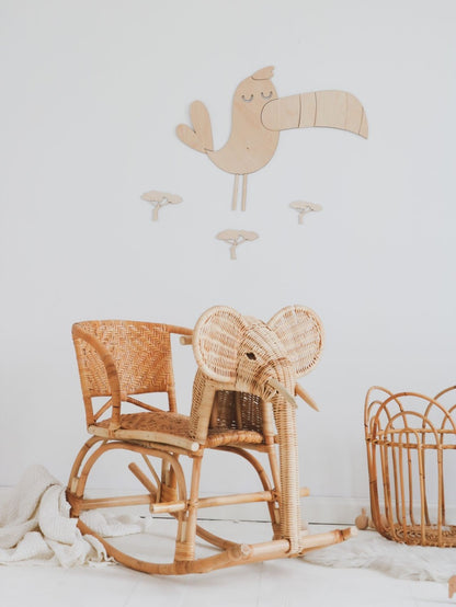 Close-up of wooden toucan and lion wall decoration pieces with baobab trees mounted above wicker furniture