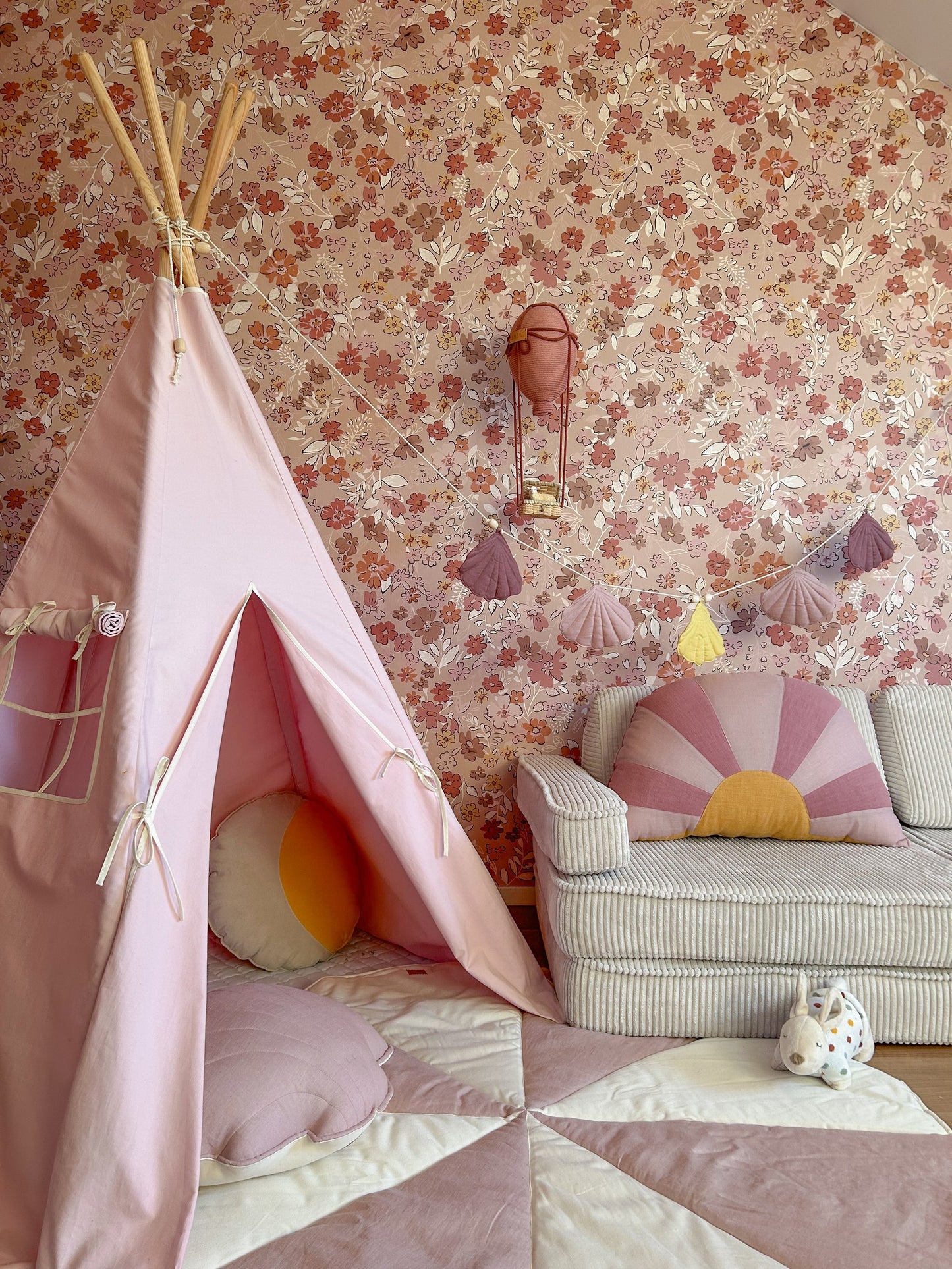 Pink cotton teepee tent set up indoors with floral wallpaper, showing open entrance and side pocket