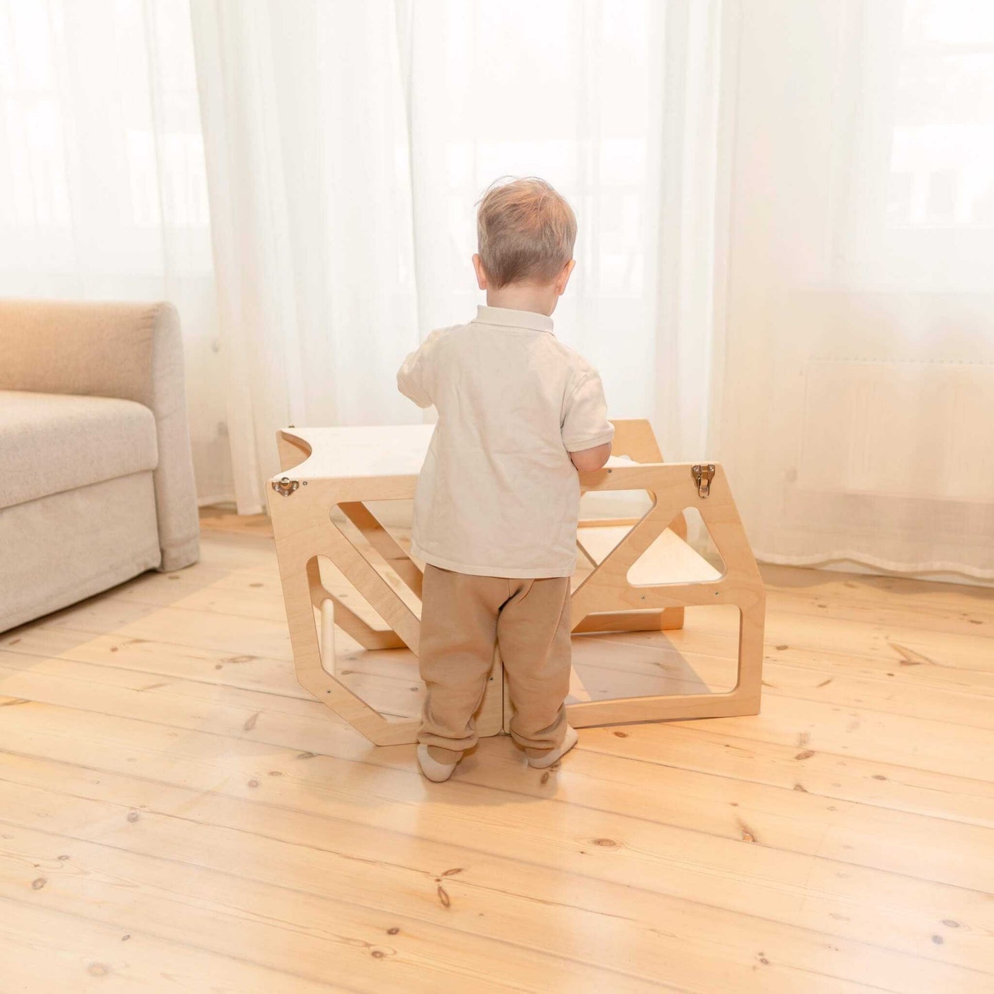 Toddler using natural wood Modustep tower as independent standing furniture