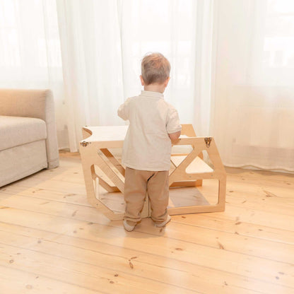 Toddler using natural wood Modustep tower as independent standing furniture
