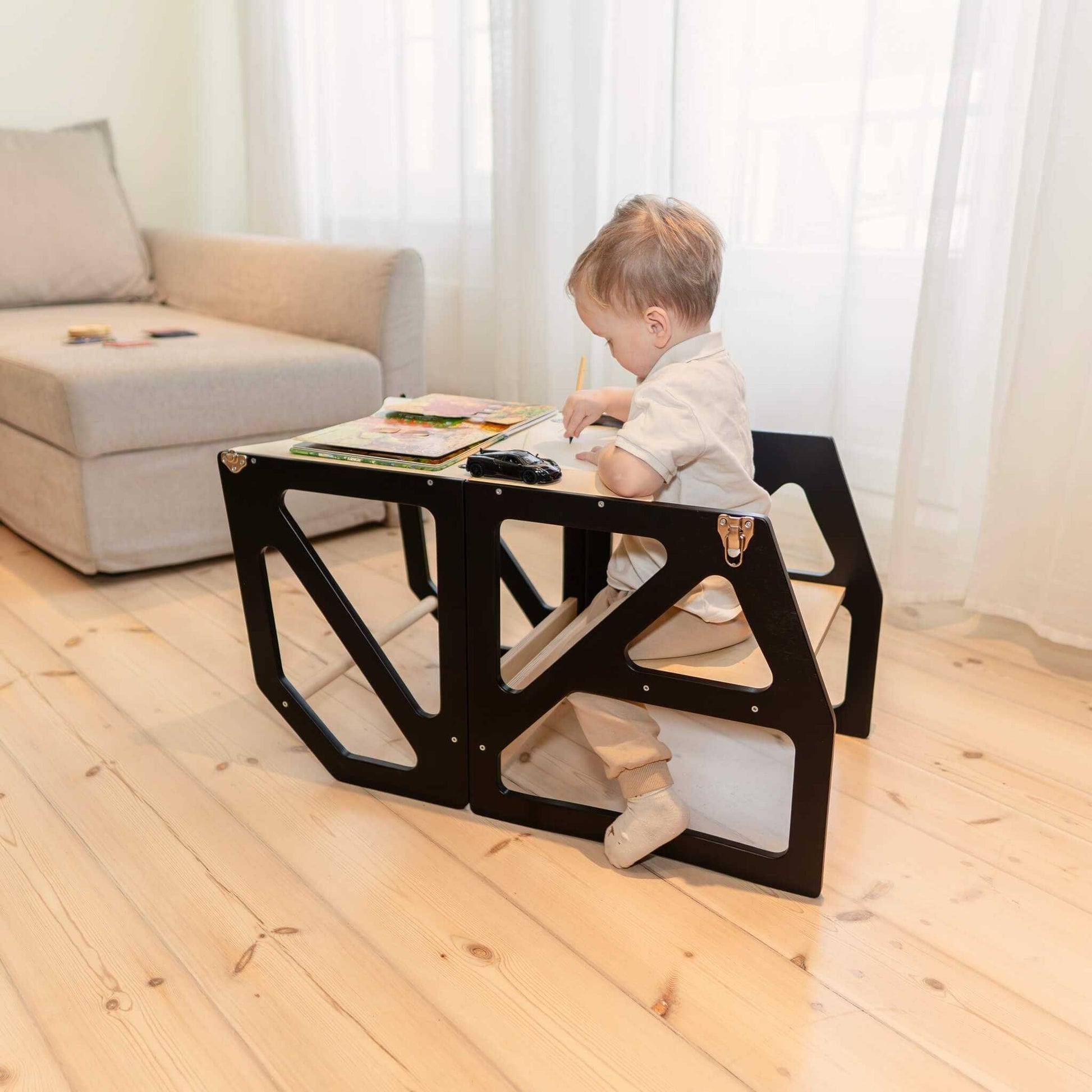 Toddler seated at low table using black Modustep chair in living space