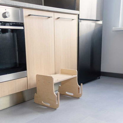 Child using natural kitchen tower to reach kitchen sink and countertop