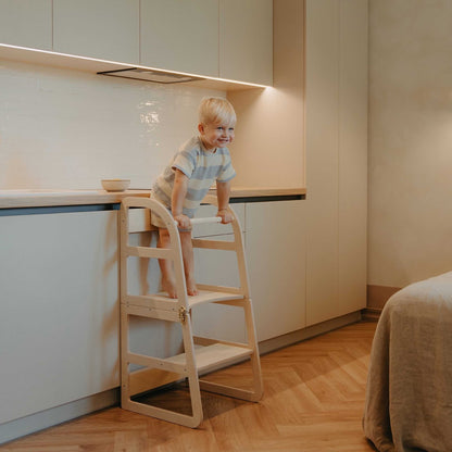 Child climbing up natural wood kitchen tower with secure side railings