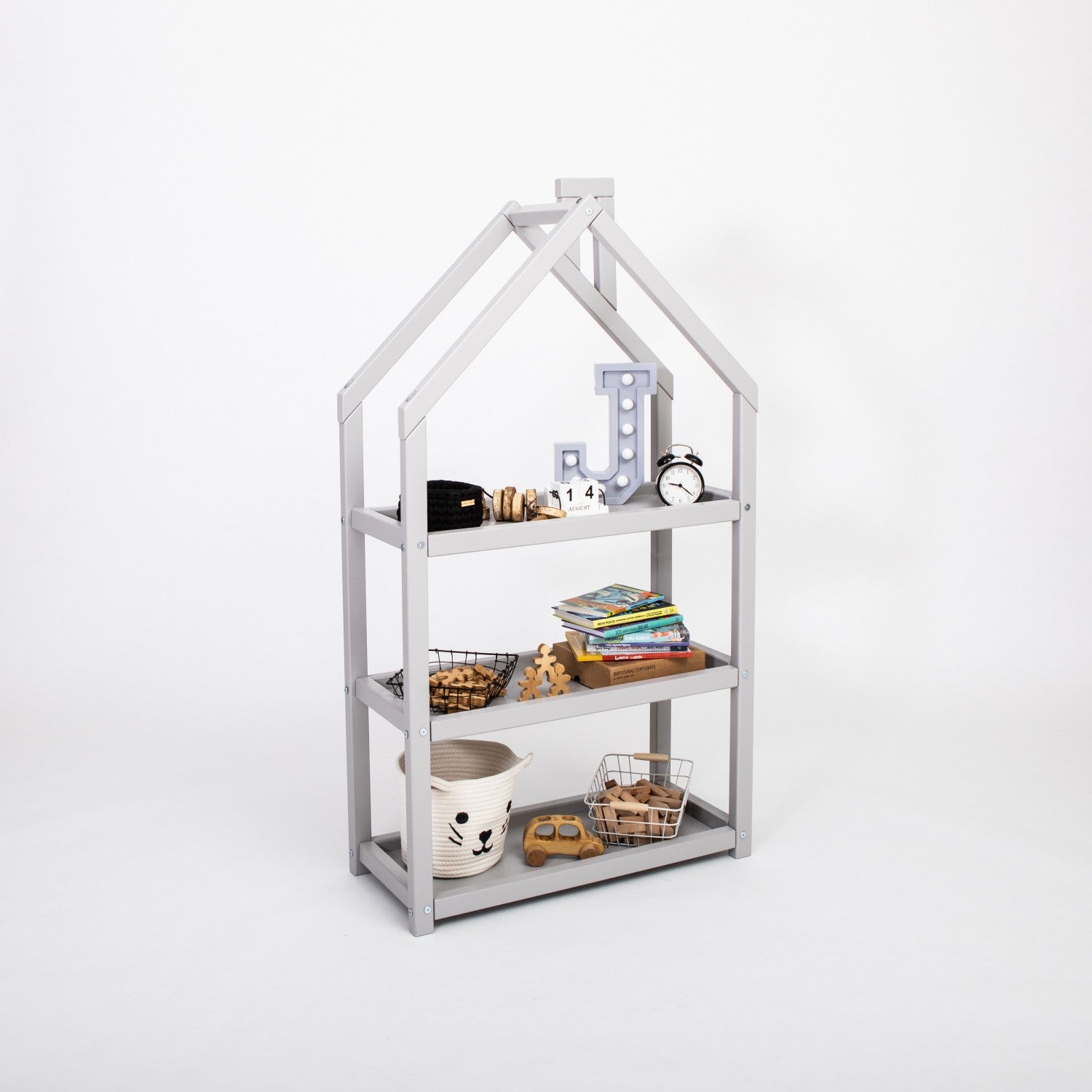 Grey house-shaped shelf with four compartments displaying books and decorative items