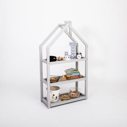 Grey house-shaped shelf with four compartments displaying books and decorative items