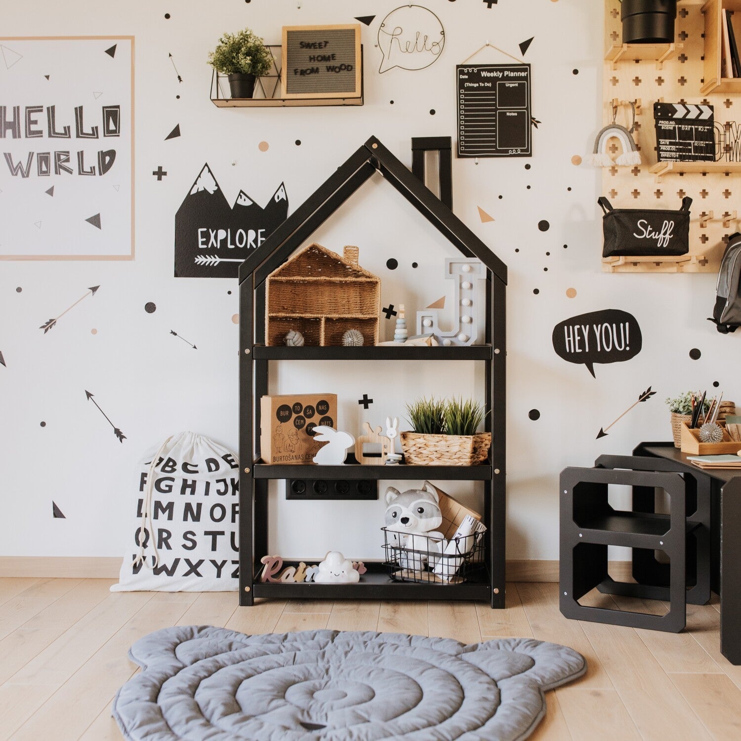 Black house-shaped shelf with decorative items and toys in modern kids room