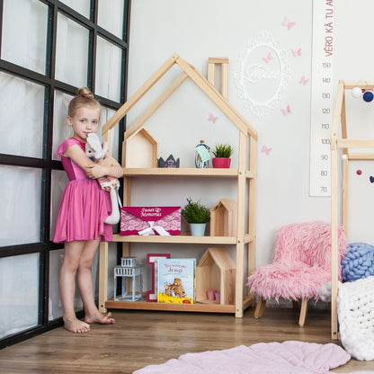 Young child reaching items on natural wood house-shaped shelf with toy storage