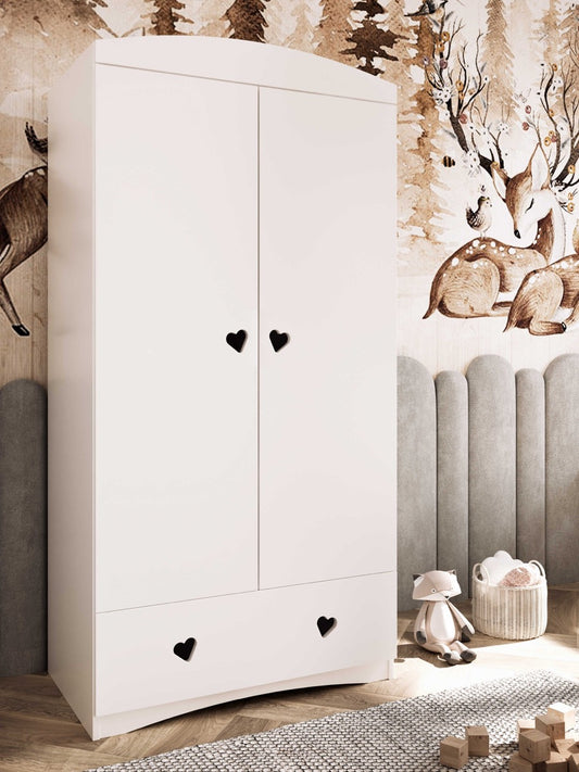 White kids wardrobe with heart-shaped handles in nursery setting with woodland wall decor
