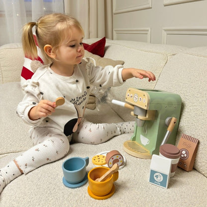 Child using wooden coffee maker with portafilter, pastry cookies displayed on plate during role-play