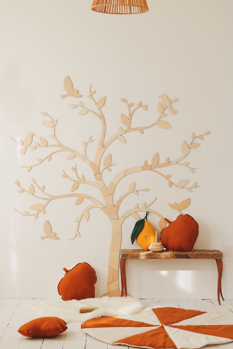 Wooden tree and birds wall decoration styled with autumn-colored cushions and home decor accessories