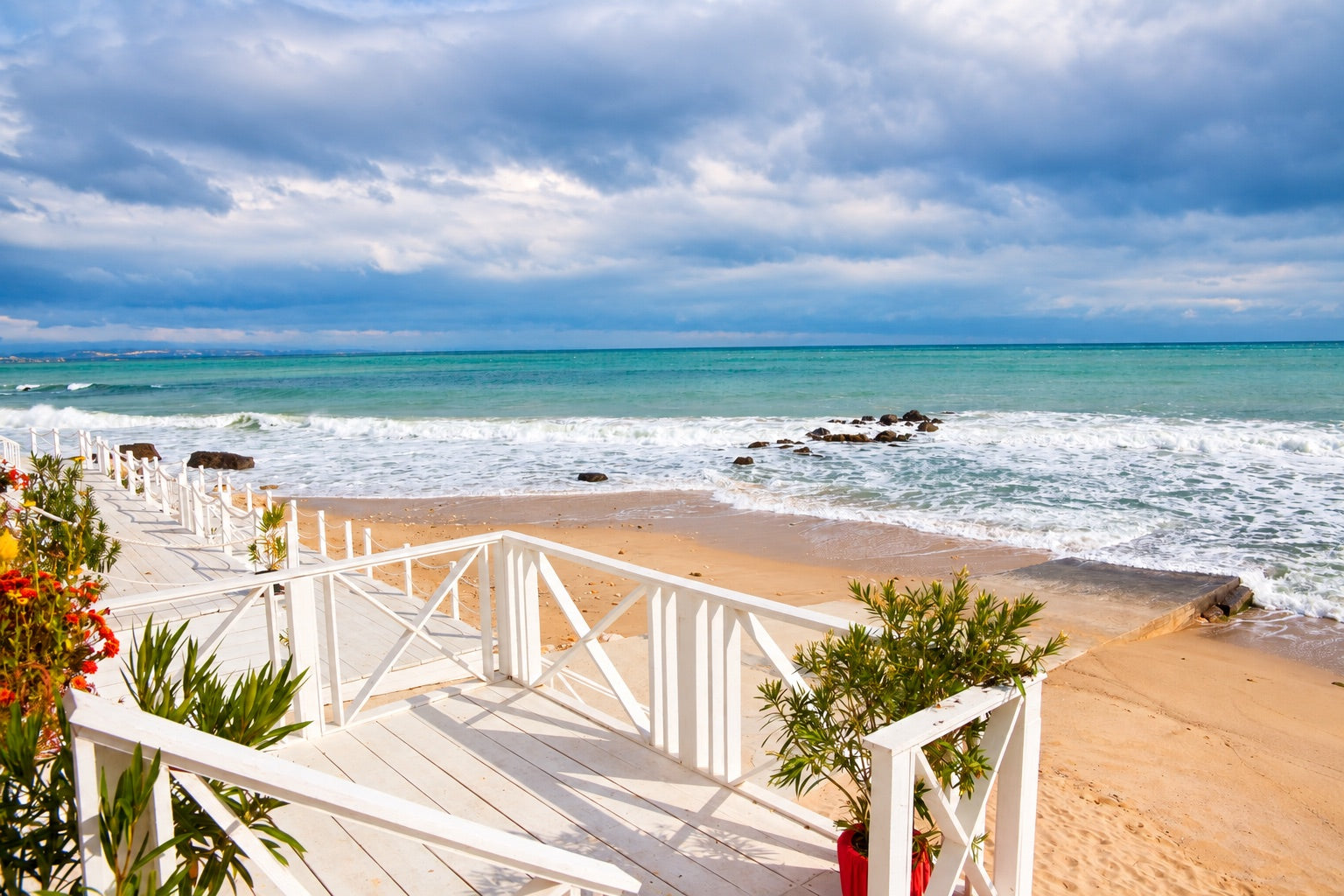 Waves meeting a sandy Black Sea beach beside a white wooden terrace